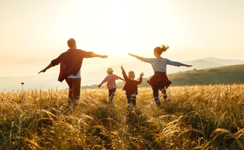hình hình ảnh mái ấm gia đình 4 người đang được nô giỡn sung sướng bên trên cánh đồng cỏ