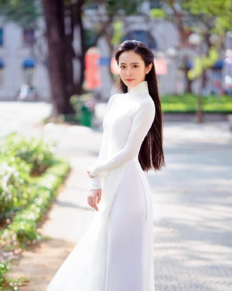 Foto eines hübschen Mädchens, das ein schönes Ao Dai auf einer sonnigen Straße trägt